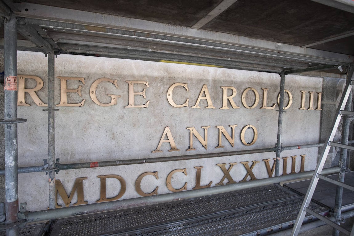 Las letras de bronce que presiden la fachada oeste de la Puerta de Alcalá, en la que Carlos III pretendía mostrarse a los madrileños como un monarca garante de la paz, se han limpiado una a una.
