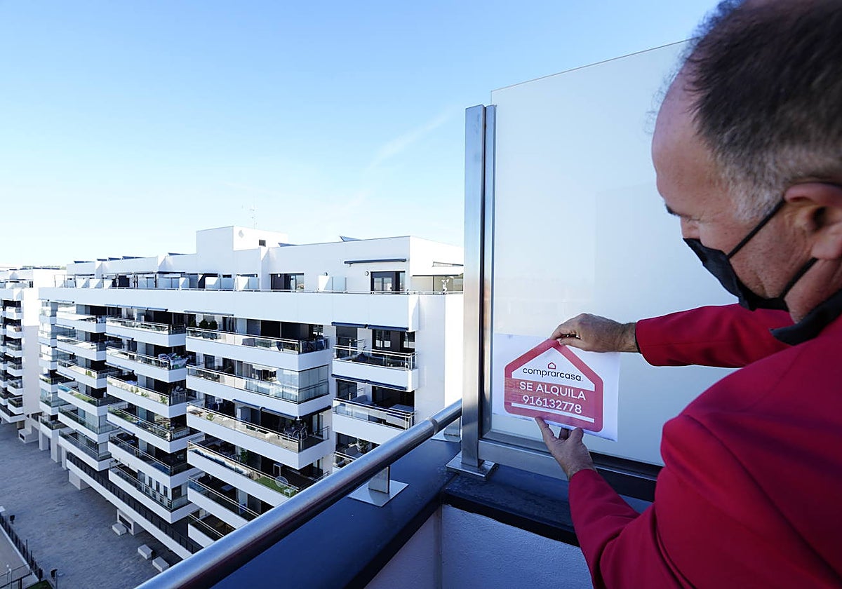 Un hombre coloca un cartel de alquiler en un piso de Rivas Vaciamadrid
