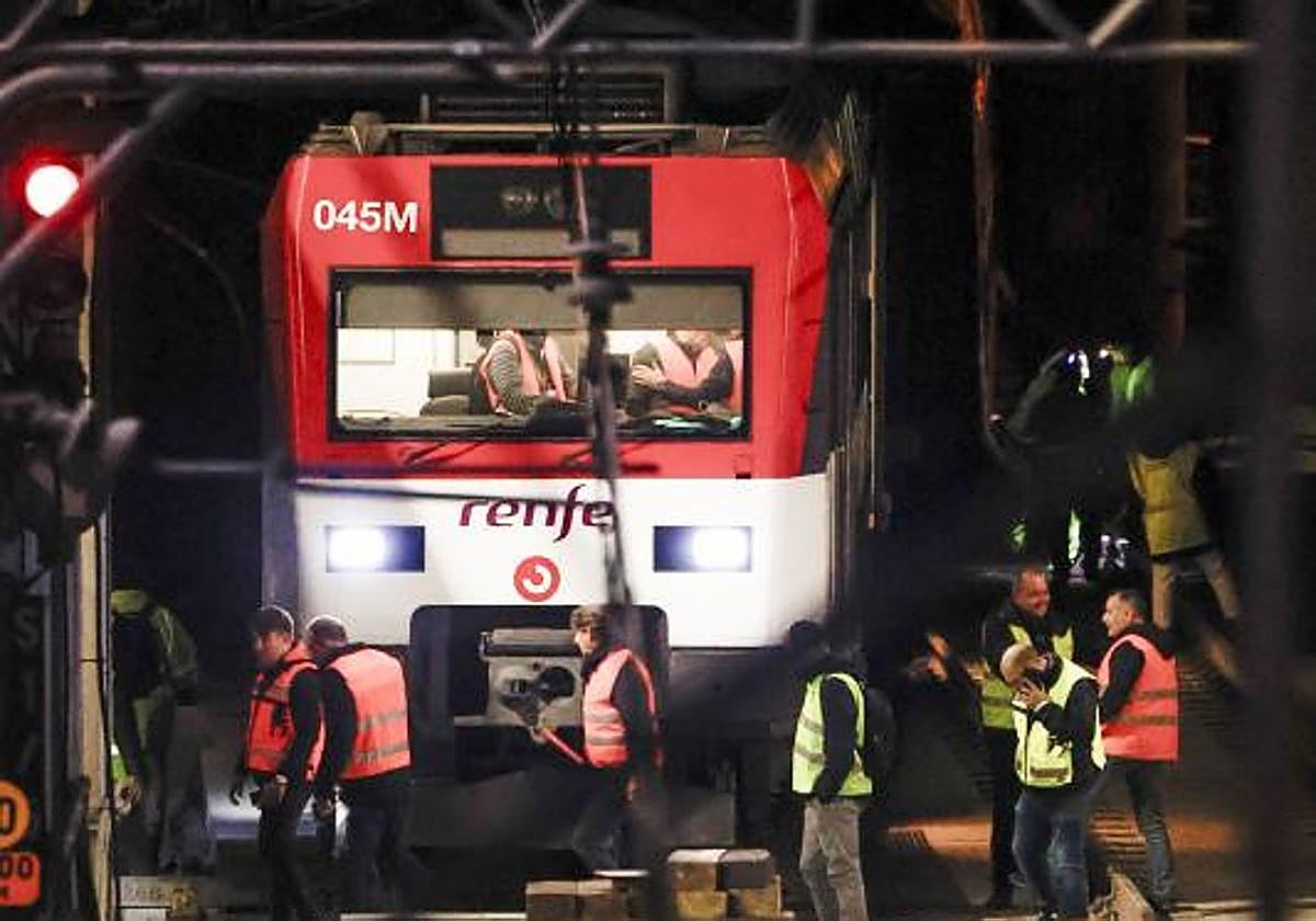 Varios operarios junto a uno de los trenes de Cercanías que descarriló en la entrada de la estación de Atocha