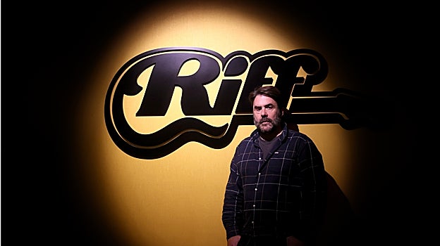 Chris Ortiz delante de un cartel de la productora de eventos