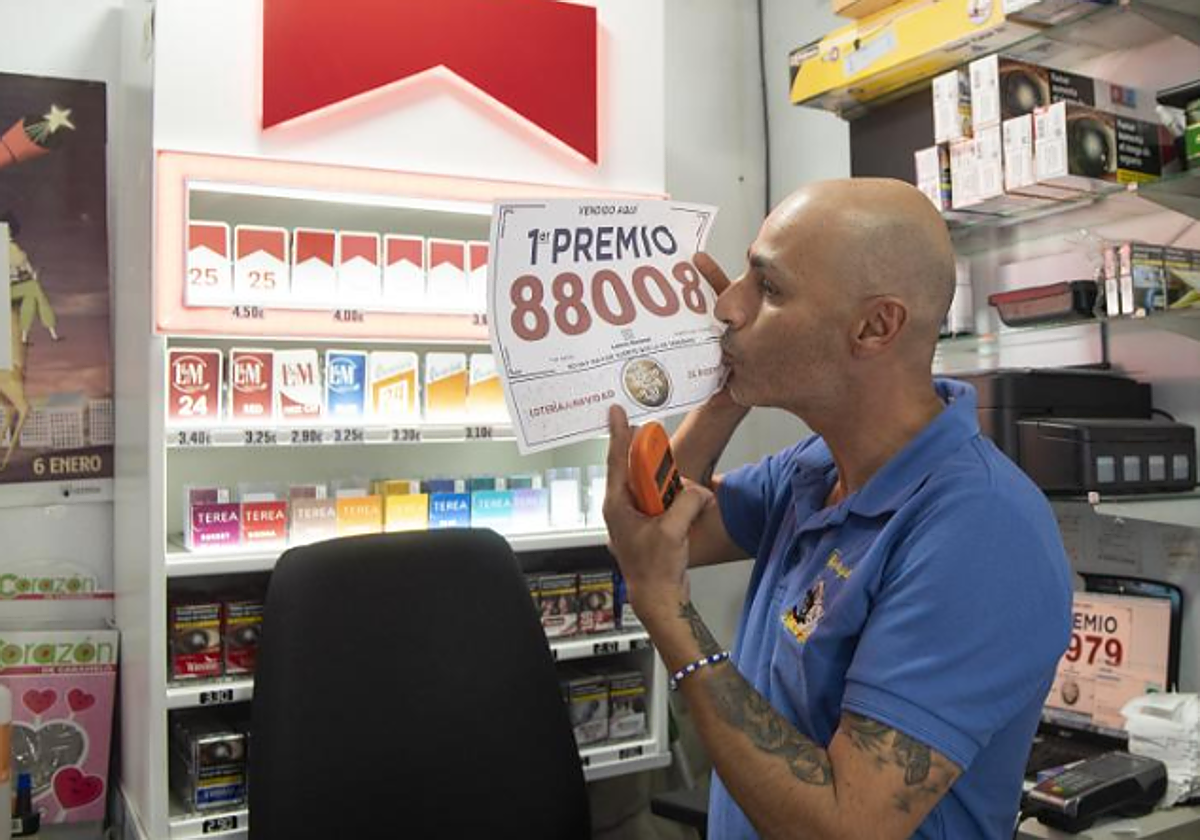 El dueño de la Administración «Los Tres Gatitos» de Puerto del Carmen, Jonathan Torres, besa el cartel del 88008