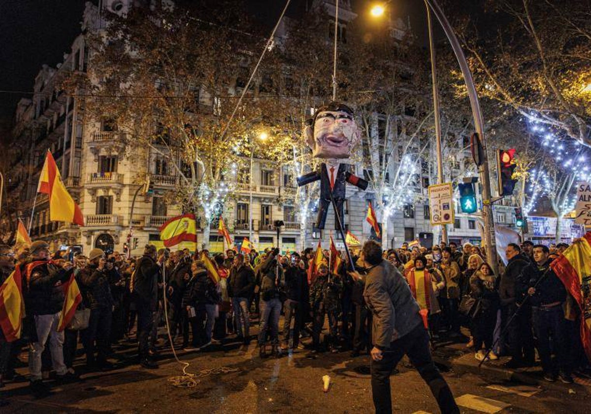 Manifestantes apalean a un muñeco que simula ser Pedro Sánchez, en la calle Ferraz