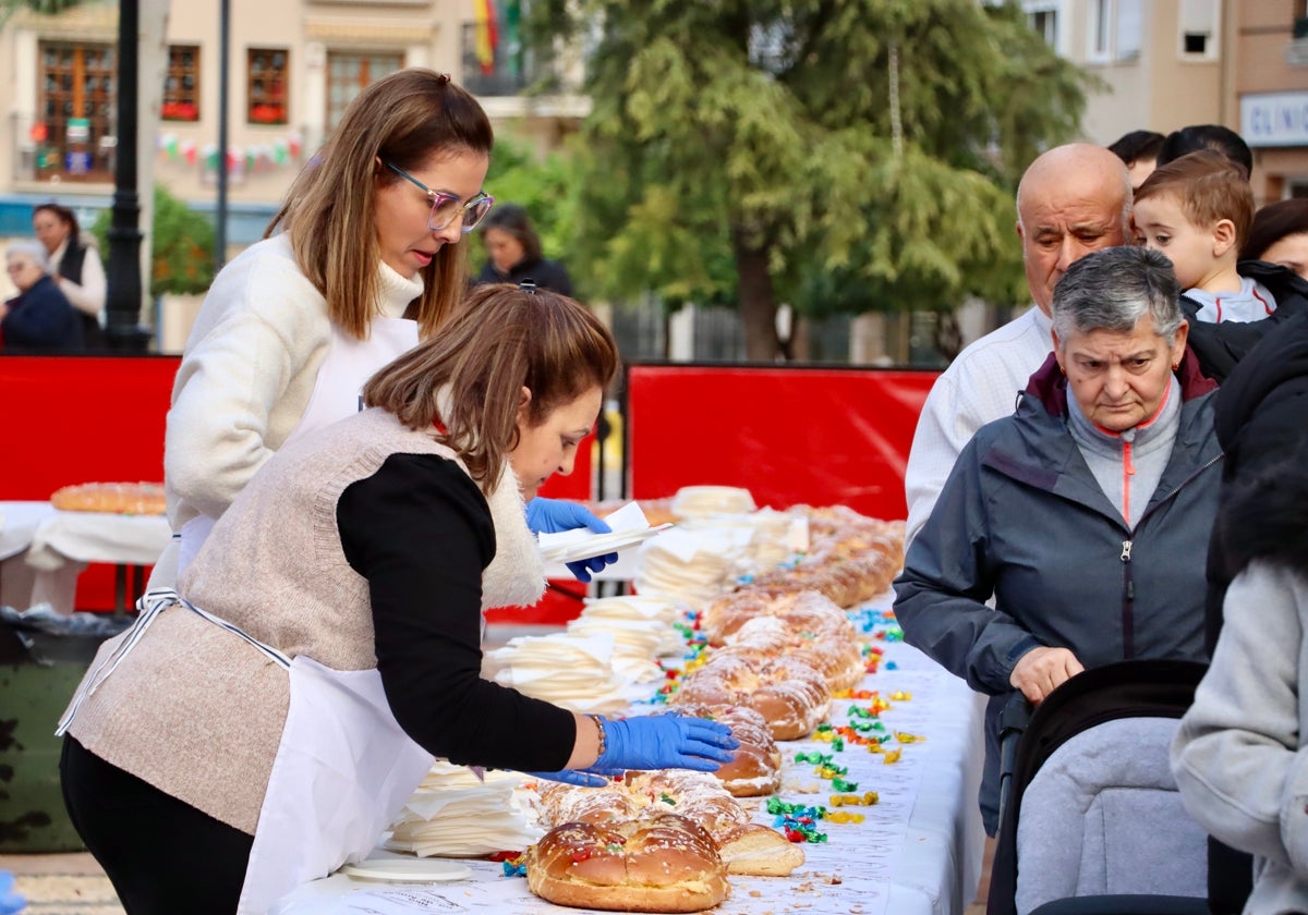 Dos mujeres cortan raciones del Roscón Gigante de Reyes en Lucena