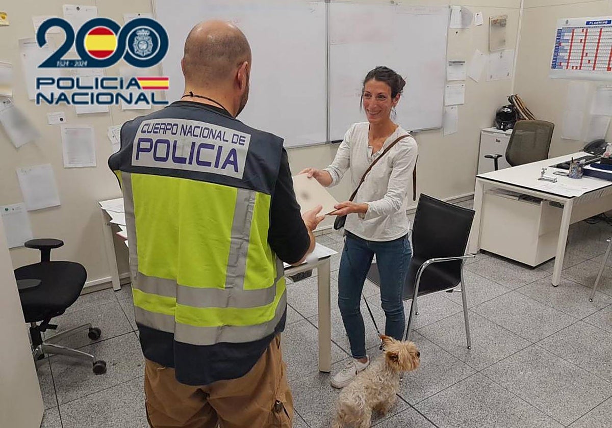 Imagen de un agente de la Policía Nacional entregando el ordenador a su propietaria