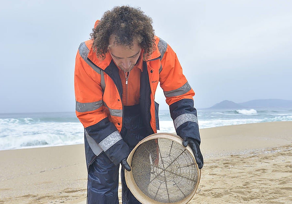 Un operario tamiza la arena para recoger pellets, este lunes en la playa de Queiruga, en Porto do Son (La Coruña)