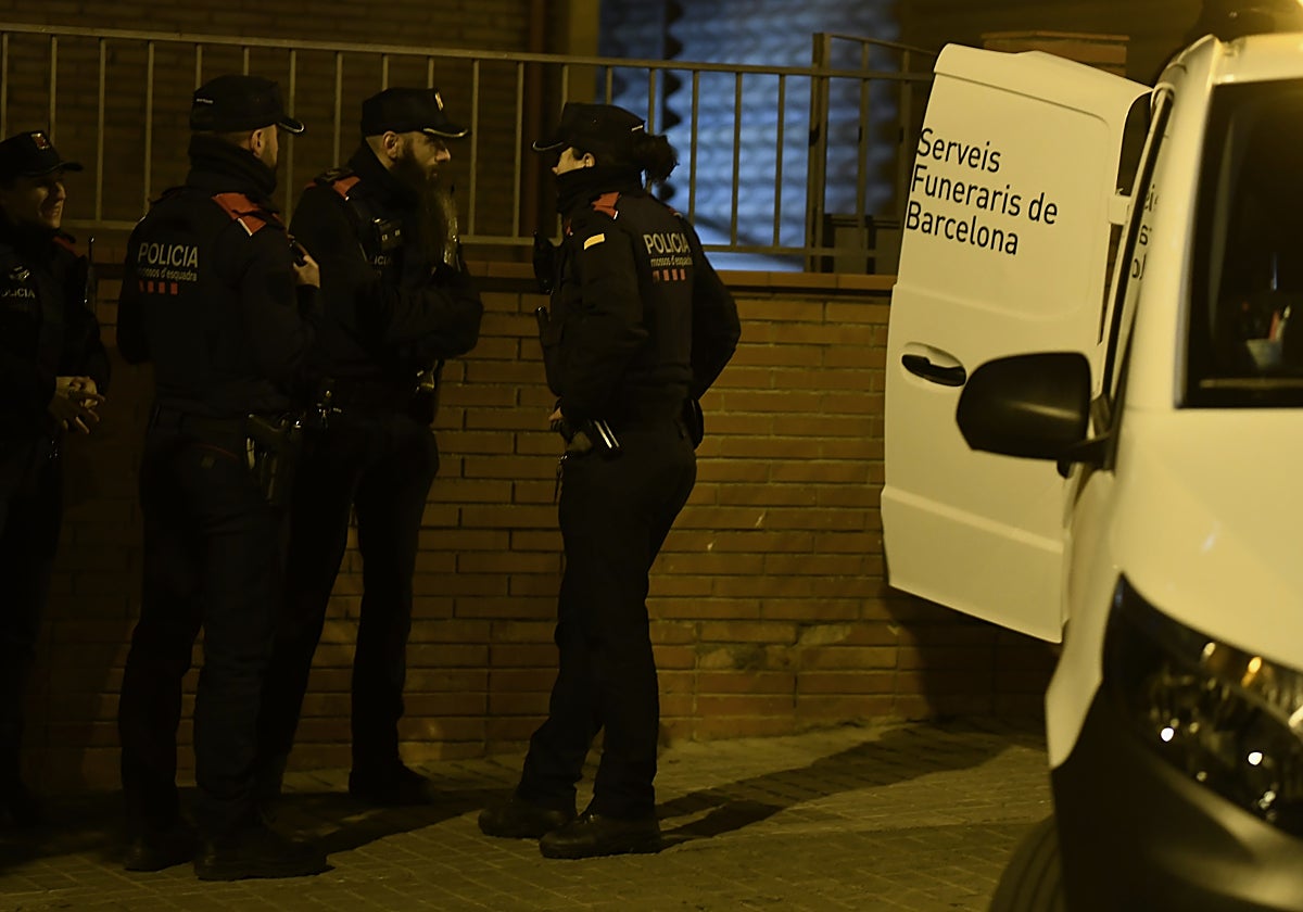 Agentes de los Mossos d'Esquadra, junto al furgón de servicios funerarios, ante el domicilio donde se hallaron los cadáveres de padre e hijos
