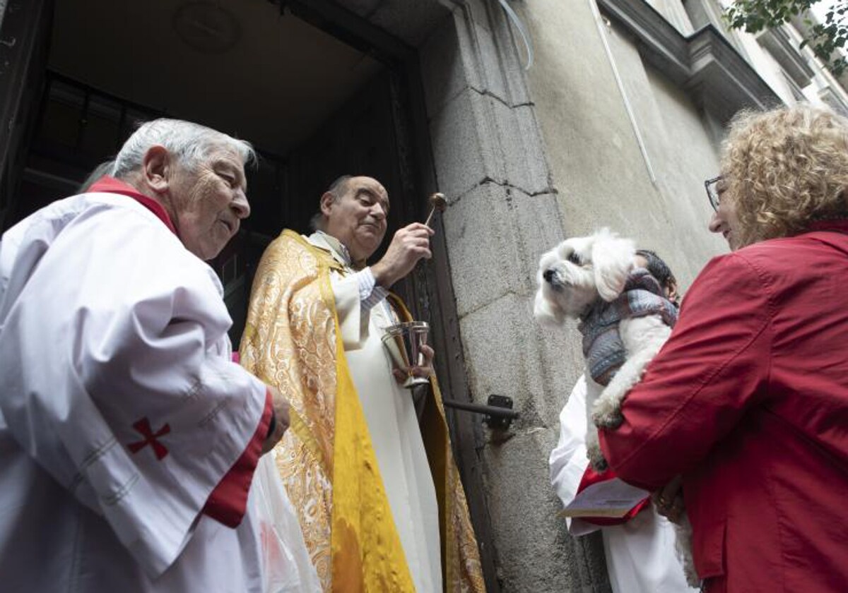 Un sacerdote bendice a un can en una de las puertas laterales de la iglesia de San Antón