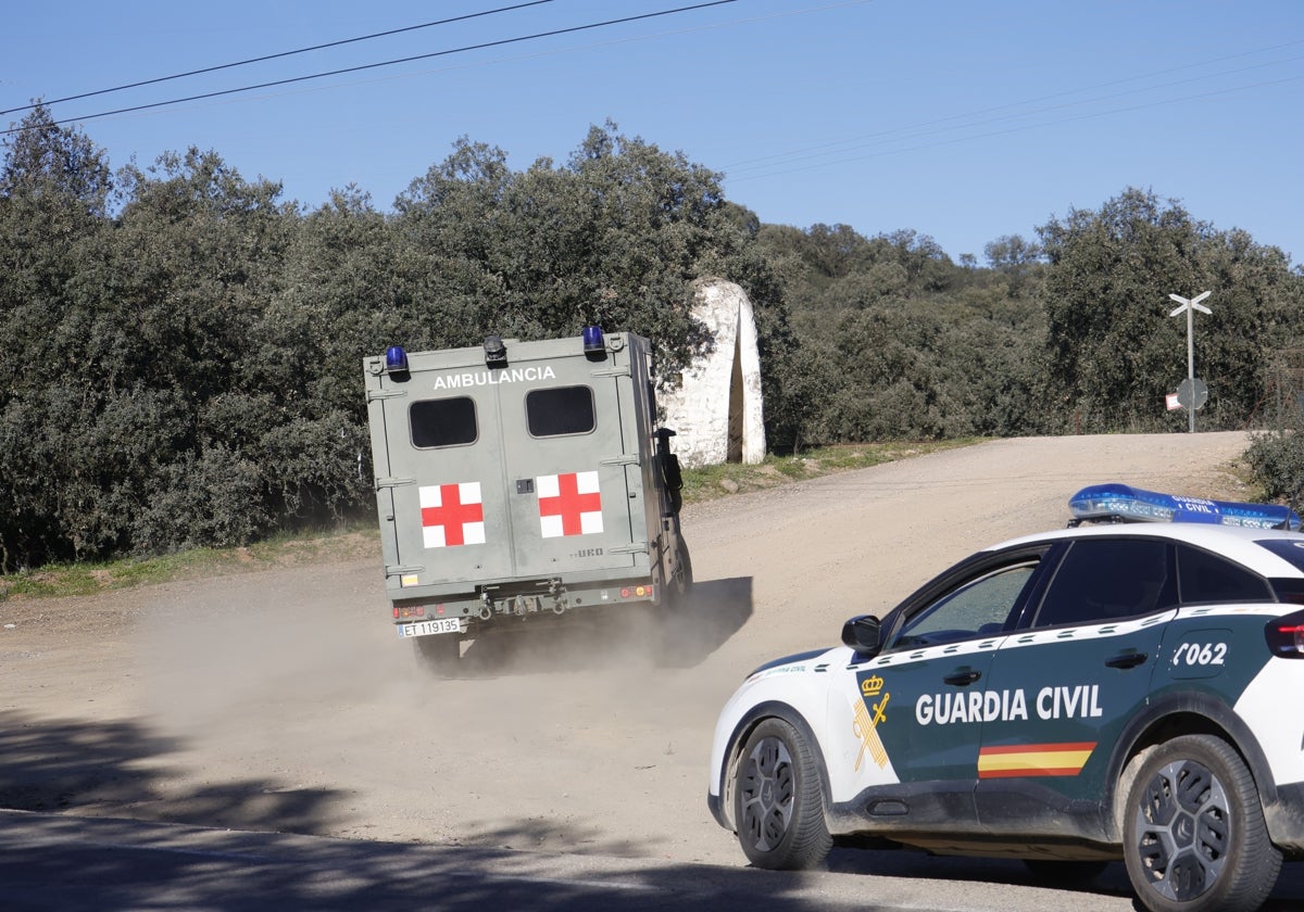 Una ambulancia escoltada por un coche dela Guardia Civil entra en el campo de maniobras de Cerro Muriano