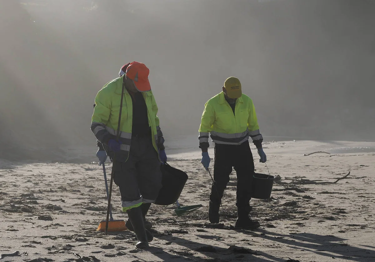 Operarios recogen pelets de la playa de Viveiro, en Lugo