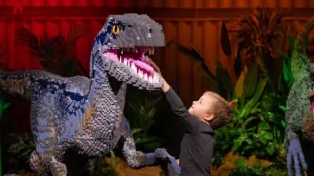 Niño tocando un dinosaurio hecho de piezas de Lego