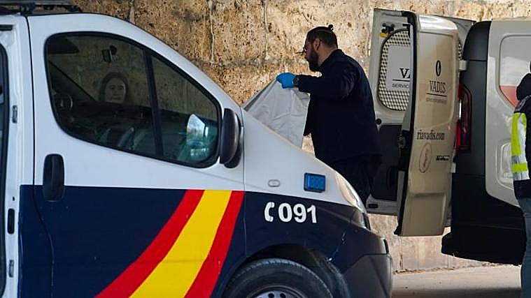 Un trabajador de servicios funerarios retira el cadáver del lugar donde han sucedido los hechos, bajo el Puente del Real