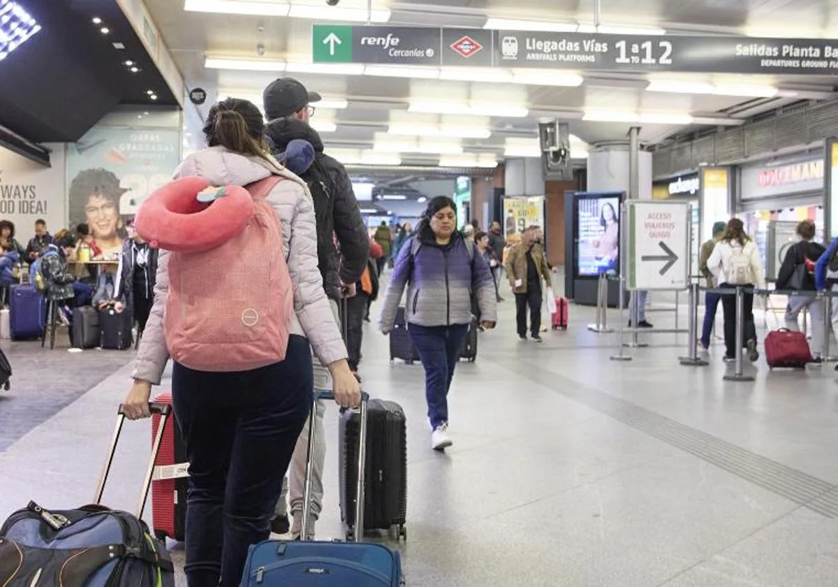 Varias personas con maletas en la estación Almudena Grandes-Atocha Cercanías