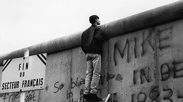 Joven mirando a través del muro de Berlín en 1989
