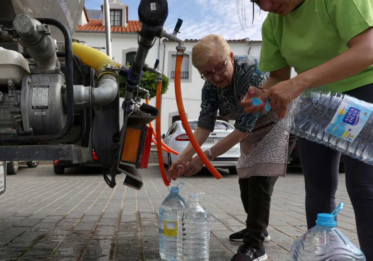 Dos vecinas de Alcaracejos, en Córdoba, llenando botellas de agua con un camión cisterna