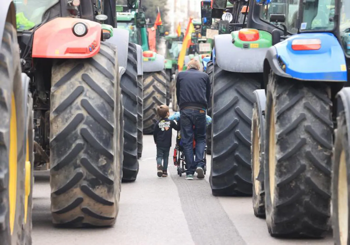 Padre e hijo caminan entre los tractores por una calle de Madrid