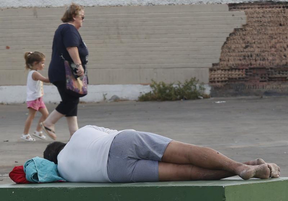 Un hombre echado en un banco en el barrio sevillano de Los Pajaritos