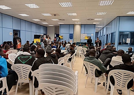Imagen secundaria 1 - Decenas de inmigrantes en una de las salas de asilo del aeropuerto de Barajas; en las imágenes de la derecha, un hombre sostiene en un papel la ruta aérea de su grupo hasta alcanzar el campamento de emergencia de Alcalá de Henares.