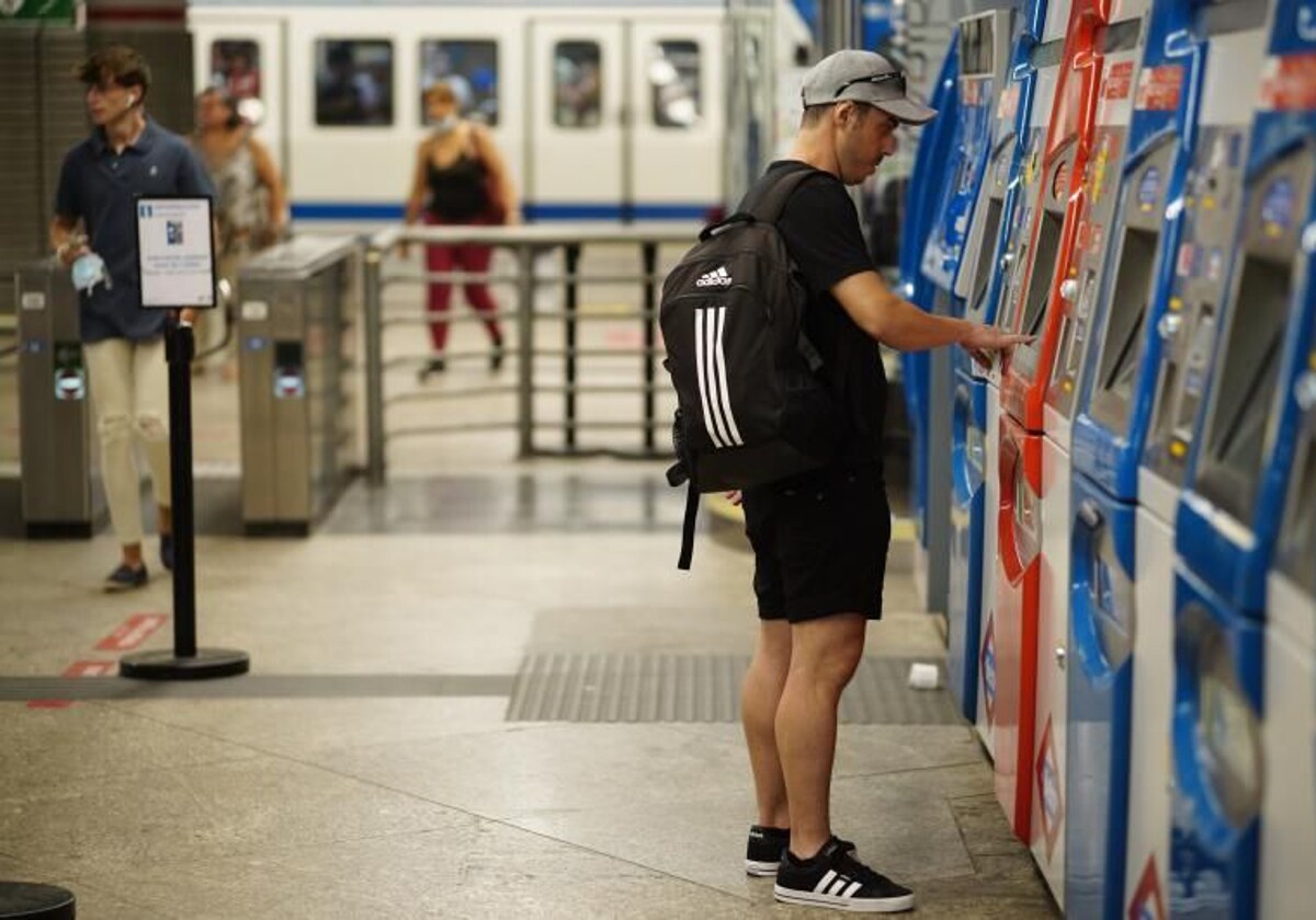 Un usuario sacando su billete o abono en una máquina expendedora de Metro