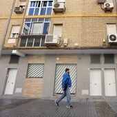 Un vecino camina delante de una hilera de apartamentos en el barrio de La Viñuela