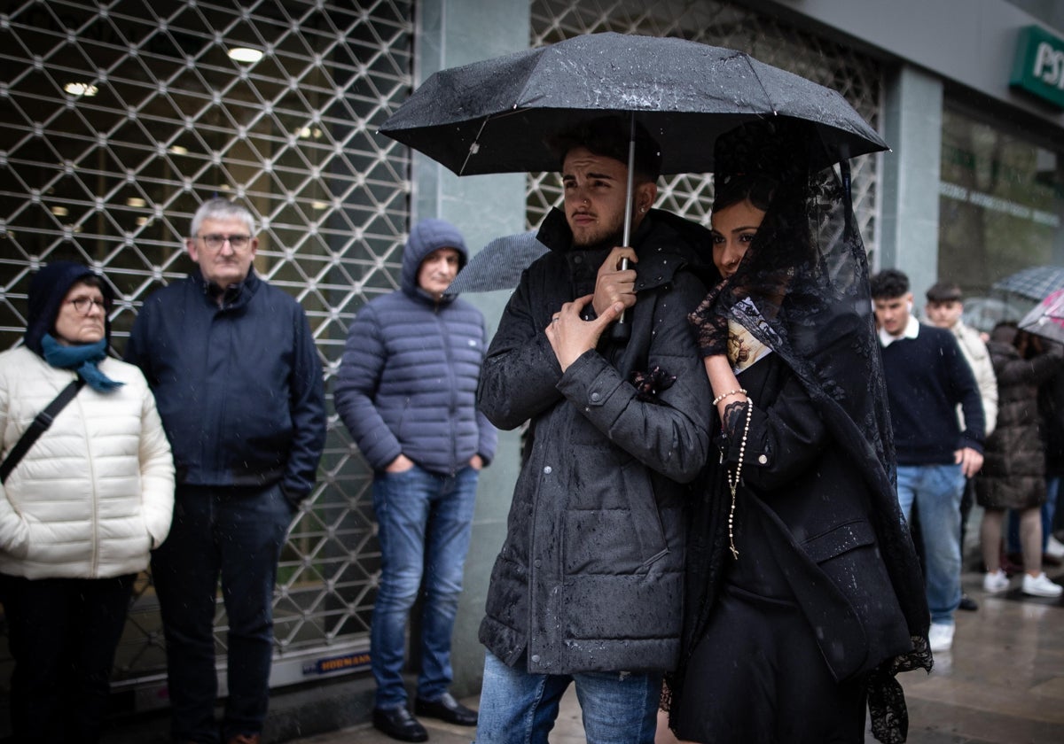 Una mujer de mantilla y un cofrade se refugian de la lluvia el pasado miércoles