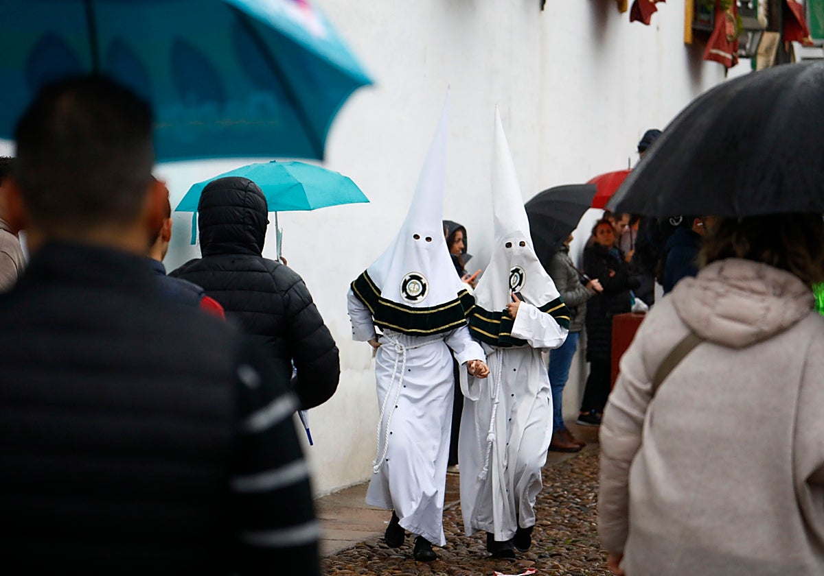 Nazarenos de la hermandad de la Paz de Córdoba entre paraguas este Miércoles Santo