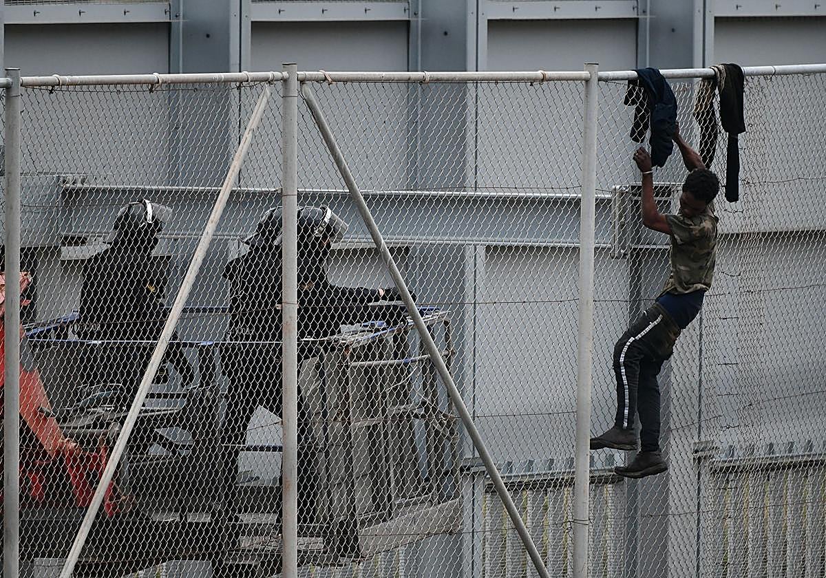Imagen de archivo de dos agentes acercándose a un inmigrante que intentaba saltar la valla de Ceuta en abril de 2021
