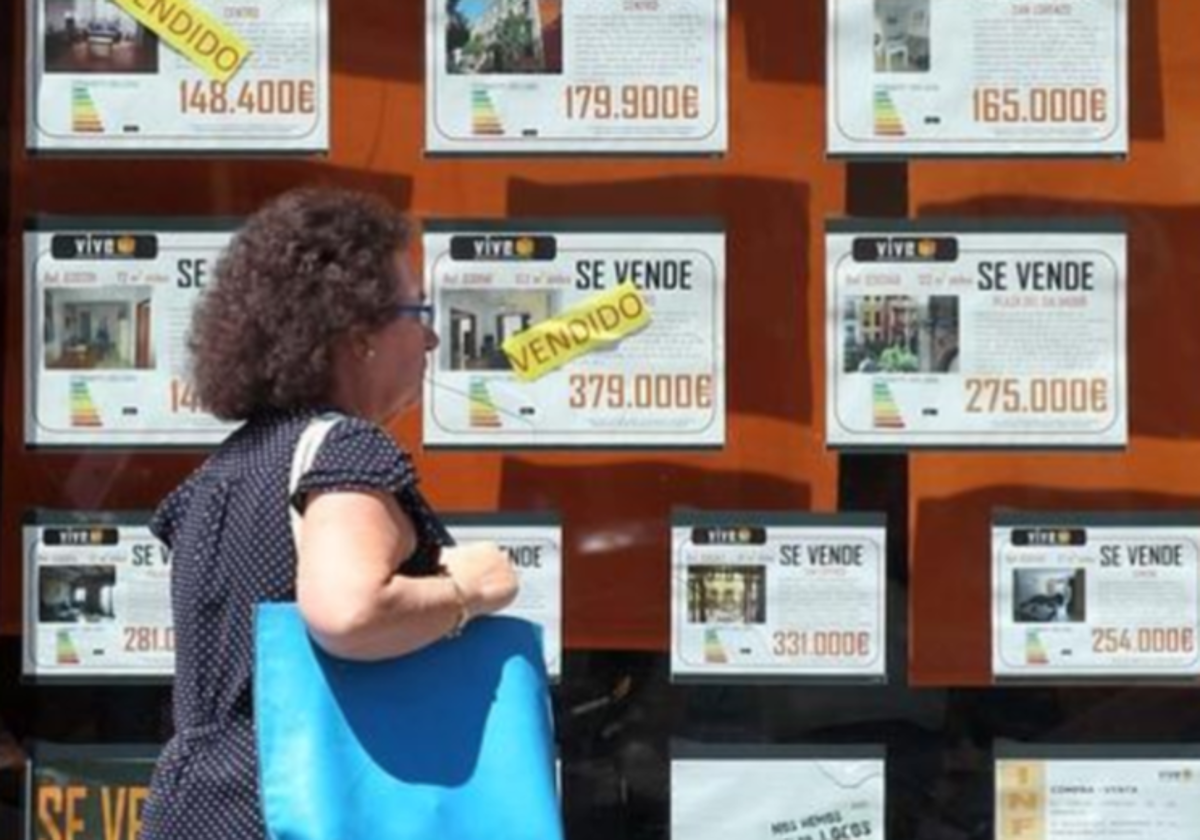 Una mujer pasea frente a una inmobiliaria con pisos en venta, en foto de archivo