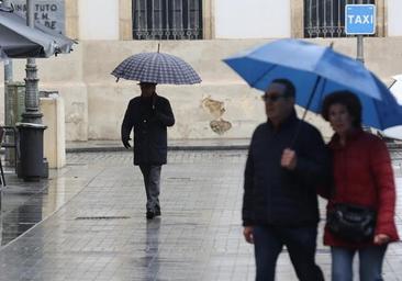 Varios viandantes bajo la lluvia por el centro de Córdoba