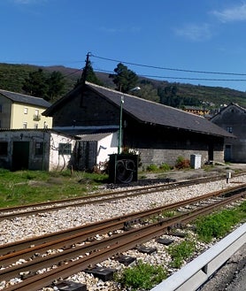 Imagen secundaria 2 - Arriba, Luis Mateo Díez posa en el despacho de su casa en Madrid. Abajo, con su hermano Antón en la etapa escolar y, a la derecha, la estación de Villablino