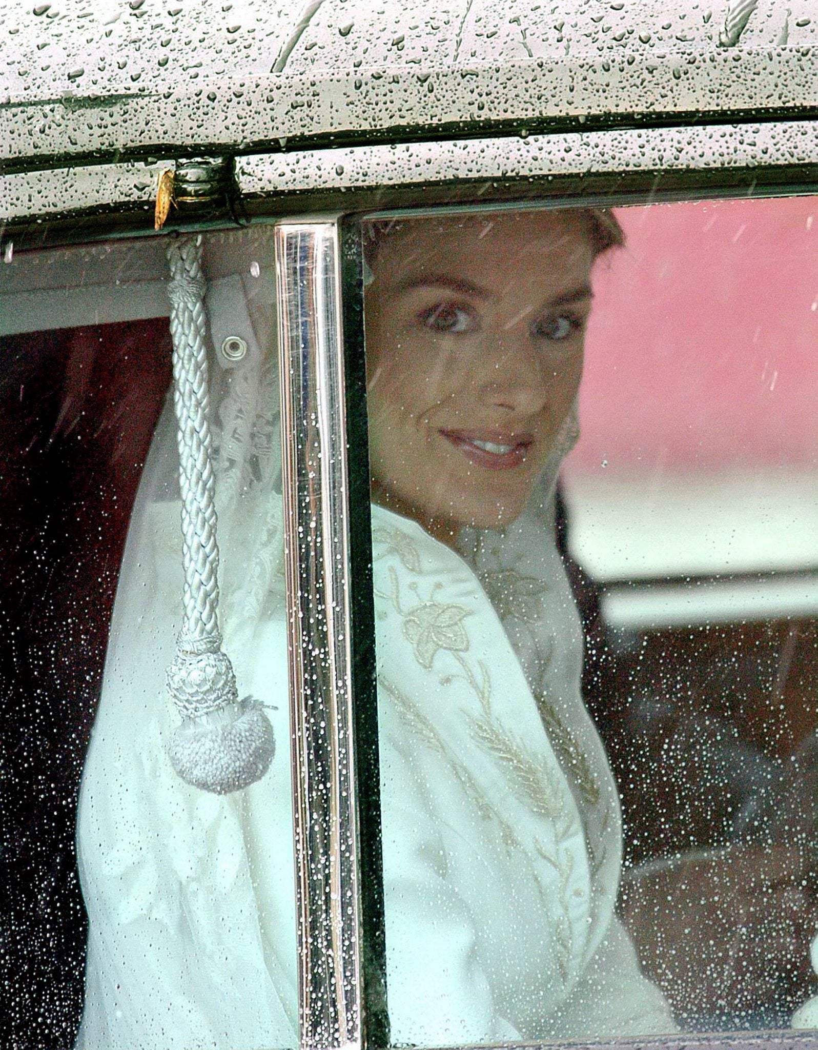 Esta fue la primera imagen que los españoles tuvieron de Doña Letizia vestida de novia. El traje, diseñado por Manuel Pertegaz, llegó tres días antes al Palacio Real y estuvo custodiado allí hasta el momento del enlace. Como en todas las bodas, era el secreto mejor guardado. A causa de la lluvia, el vestido no se pudo ver entero hasta que la novia no bajó del Rolls-Royce en la misma puerta de la catedral. Se calcula que el traje pesaba unos cinco kilos. En aquel momento, los comentaristas revelaban el diseño del esperado atuendo. Inspirado en una línea princesa y de color blanco roto, la parte superior del vestido estaba ceñida al cuerpo y a las mangas. Contaba con un escote en pico, estilo chimenea, y un cuello corola, bordado en hilo de plata y oro e hilado en proceso por ambos lados que mezclaba la flor de lis, espigas, madroños y tréboles, además de una cola, decorada con los mismo símbolos, de cuatro metros y medio de largo y un perímetro de 16 metros. Se habló de él como «el más austero de la realeza europea», pues Doña Letizia pidió confeccionar un traje sencillo, sin excesos. Se pagó un precio simbólico por el traje de 6.000 euros. El valor real rondaría los 45.000 euros.