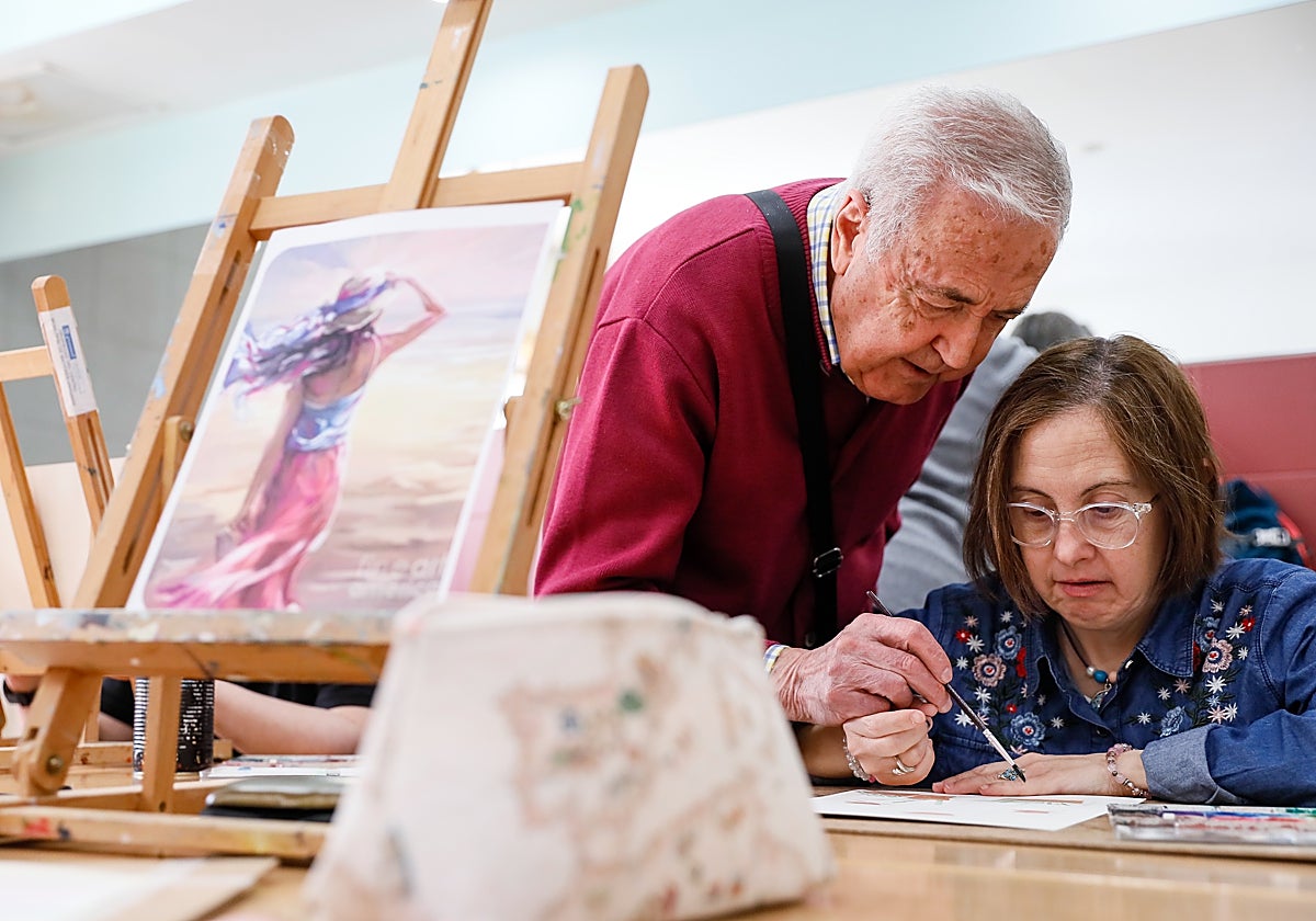 Un usuario del Centro de Mayores de La Vaguada enseña a una persona con síndrome de Down