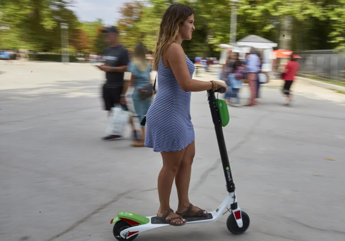 Una joven monta en patinete en foto de archivo