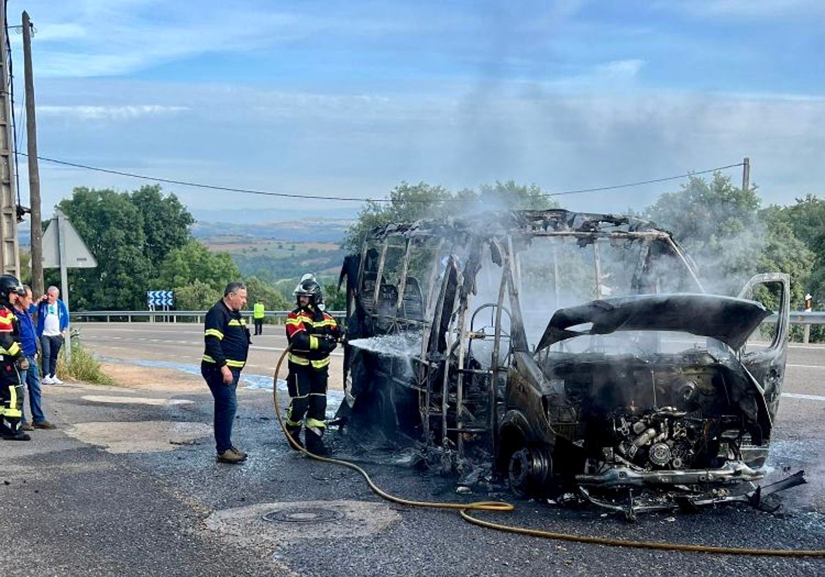 Bomberos junto al microbús incendiado