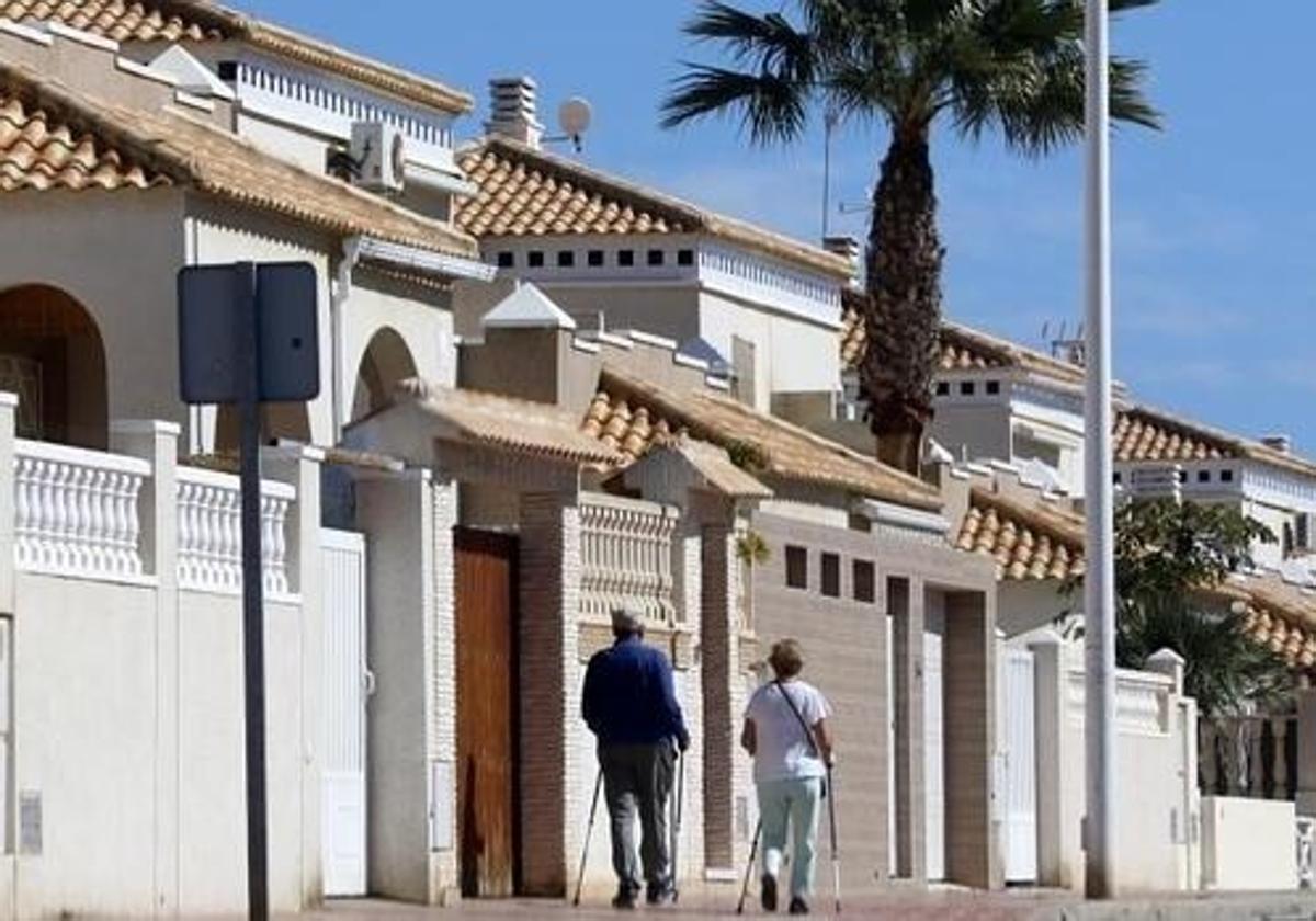 Un jubilado y una mujer transitan por una urbanización de Alicante.