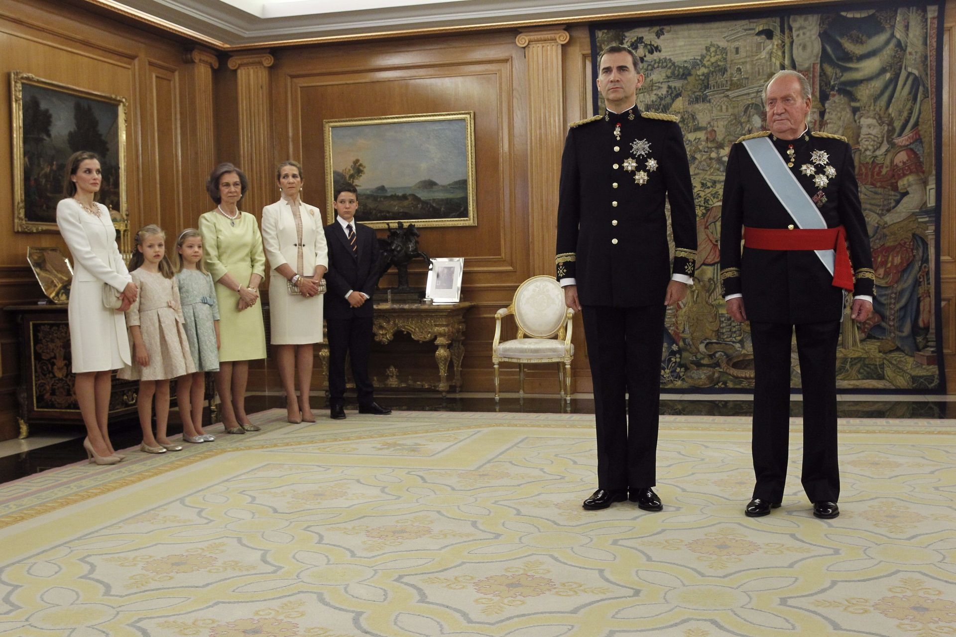 Al día siguiente de que Don Juan Carlos firmara la Ley de Abdicación, se celebró la jura y proclamación de Don Felipe como nuevo Rey de la Corona de España. En esta imagen se puede observar a Don Felipe junto a su padre, Don Juan Carlos, instantes antes de la imposición de la faja de Capitán General de las Fuerzas Armadas en la sala de Audiencias del Palacio de la Zarzuela. Al acto de la colocación de dicho fajín, que comenzó con la lectura del artículo 62 de la Constitución, acudieron Doña Letizia y sus hijas, la Princesa Leonor y la Infanta Sofía; y Doña Sofía y la Infanta Elena junto a su hijo mayor y sobrino del Rey, Felipe Juan Froilán; además de los altos mandos de los tres ejércitos.