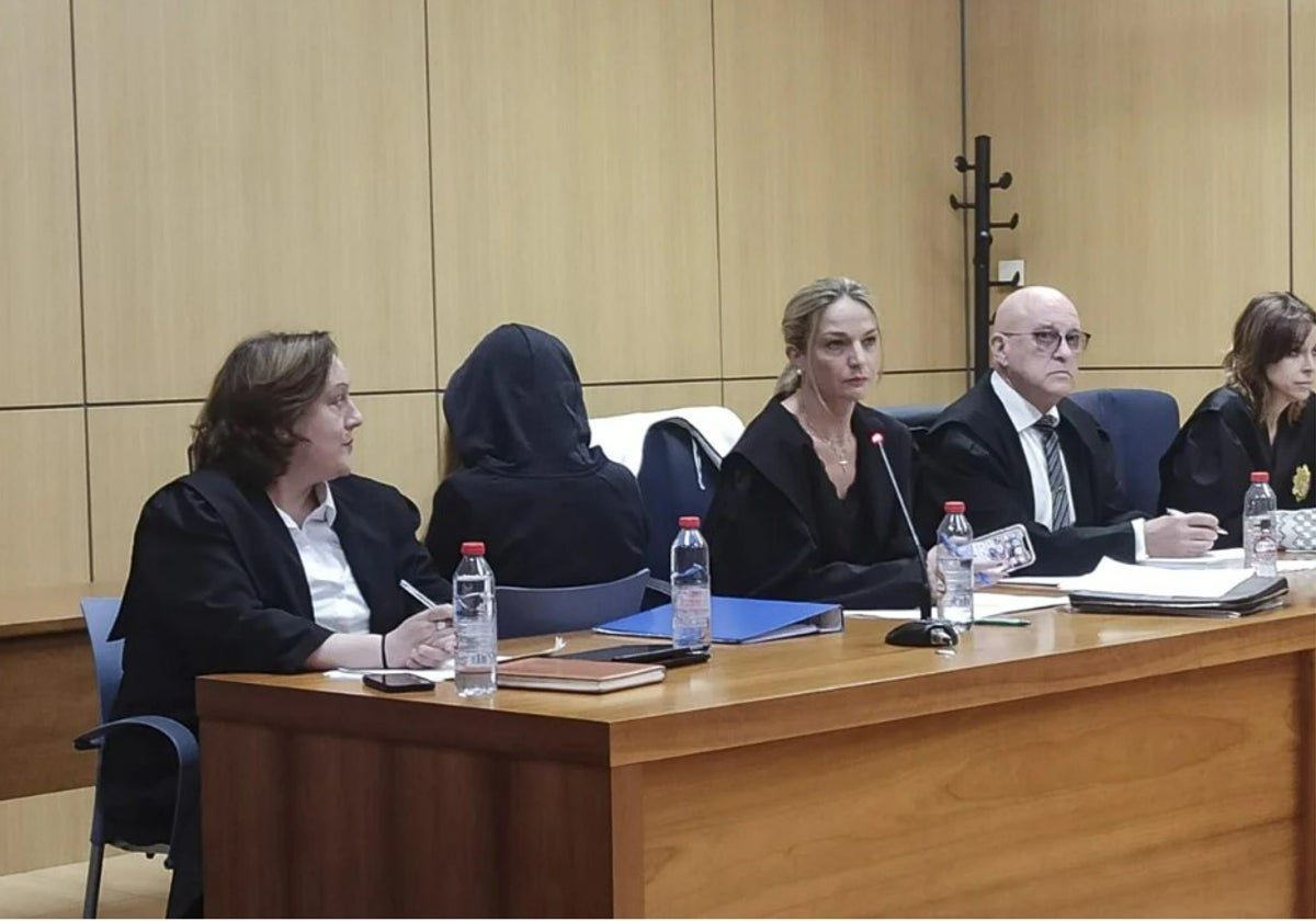 La joven que confesó haber matado a su madre, de espaldas con una capucha durante el juicio en Valencia.