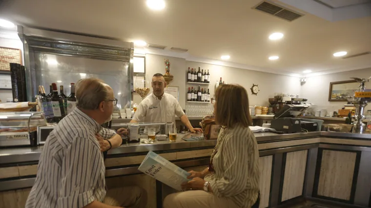 Dos clientes conversan con el camarero en la barra de Casa Pedro