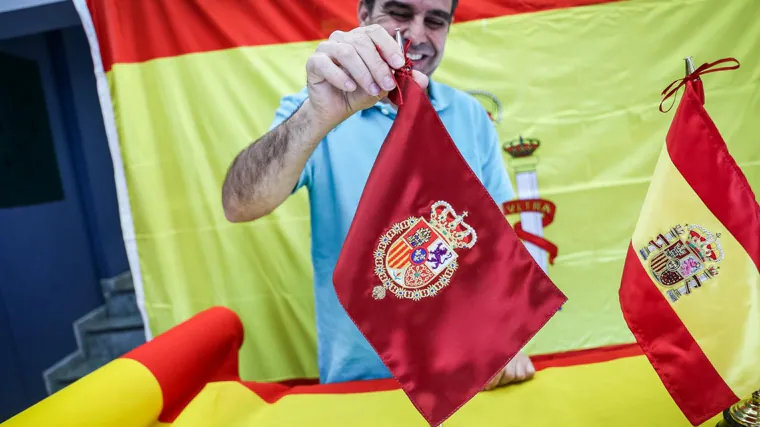 Un trabajador de Fieltros Olleros muestra algunas de las banderas de España que comercializan