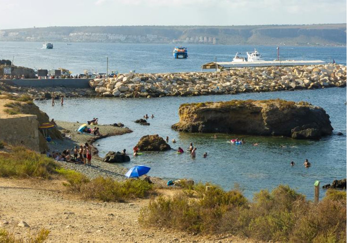 Bañistas y turistas en una de las calas de la isla de Tabarca, con vistas al fondo de la península.