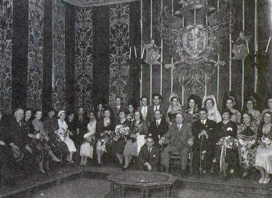 Recepción de la comisión invitada en el Salón de Plenos del Ayuntamiento de Toledo. En centro, con traje gris, Hoover, sentado entre el embajador de Estados Unidos y el alcalde Perezagua con el bastón del cargo. Delante y agachado, el periodista Adoración Gómez Camarero. Fotografía de Rodríguez
