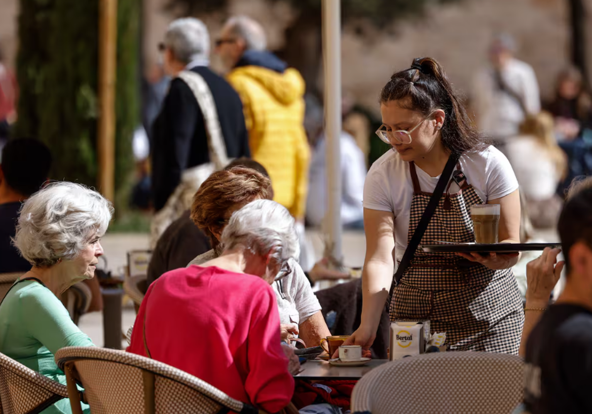 En la imagen una camarera atiende una mesa en una terraza en la ciudad de Valencia