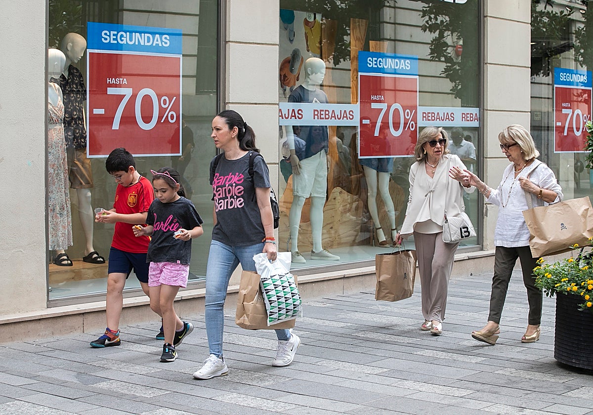 Varias personas con bolsas de compras en rebajas por la calle Cruz Conde