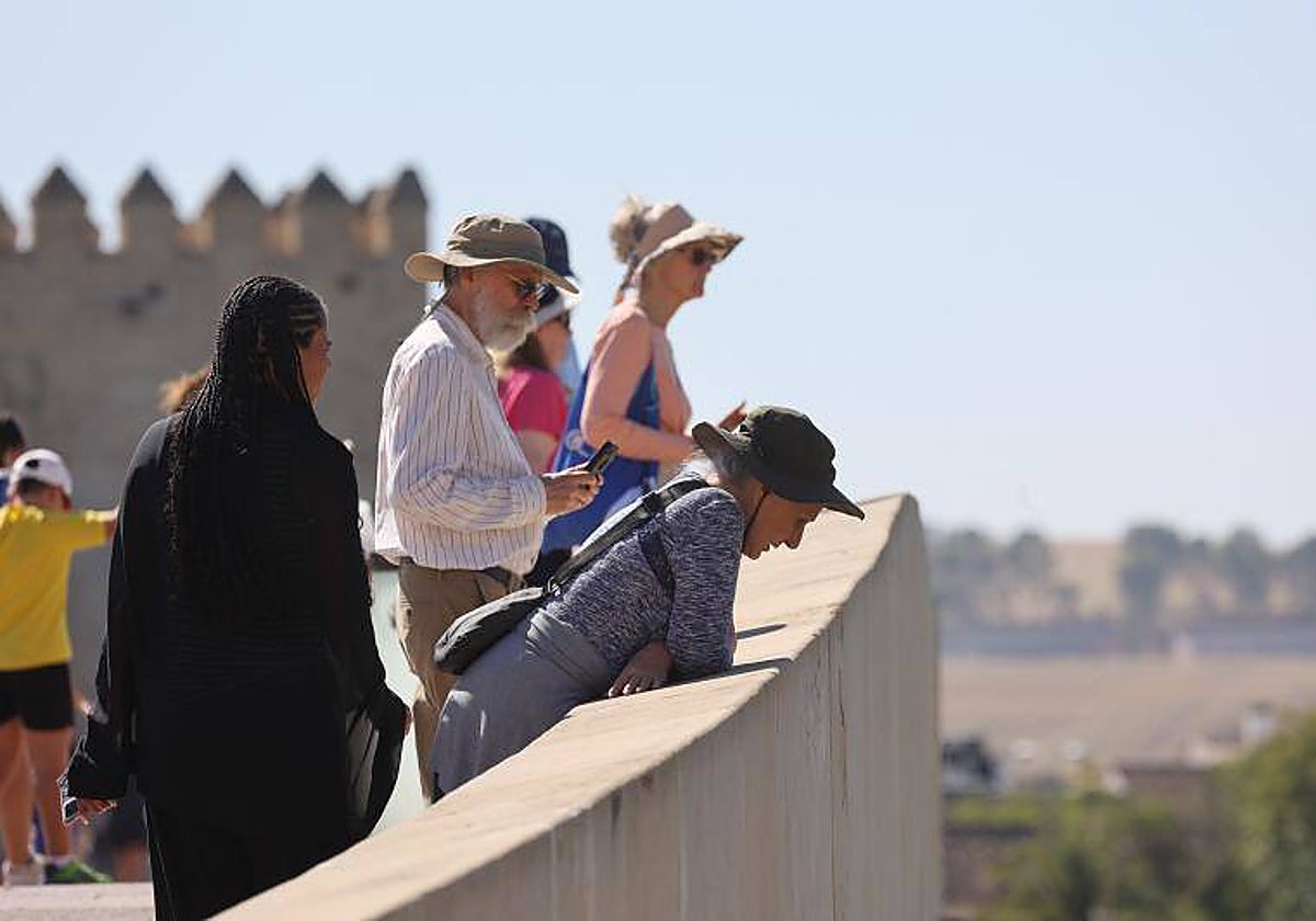 Turistas protegidos del calor en el Puente de San Rafael en Córdoba