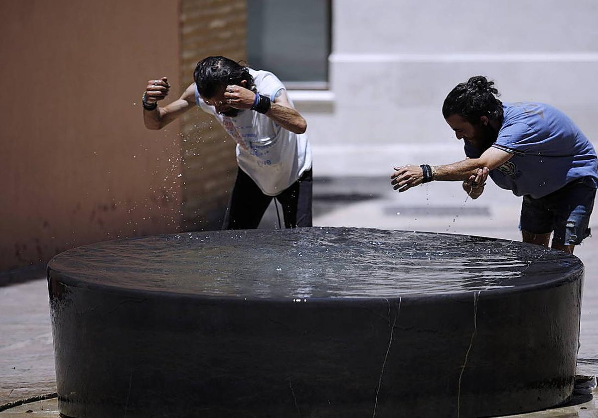 Dos personas se refrescan en una fuente del centro de Málaga