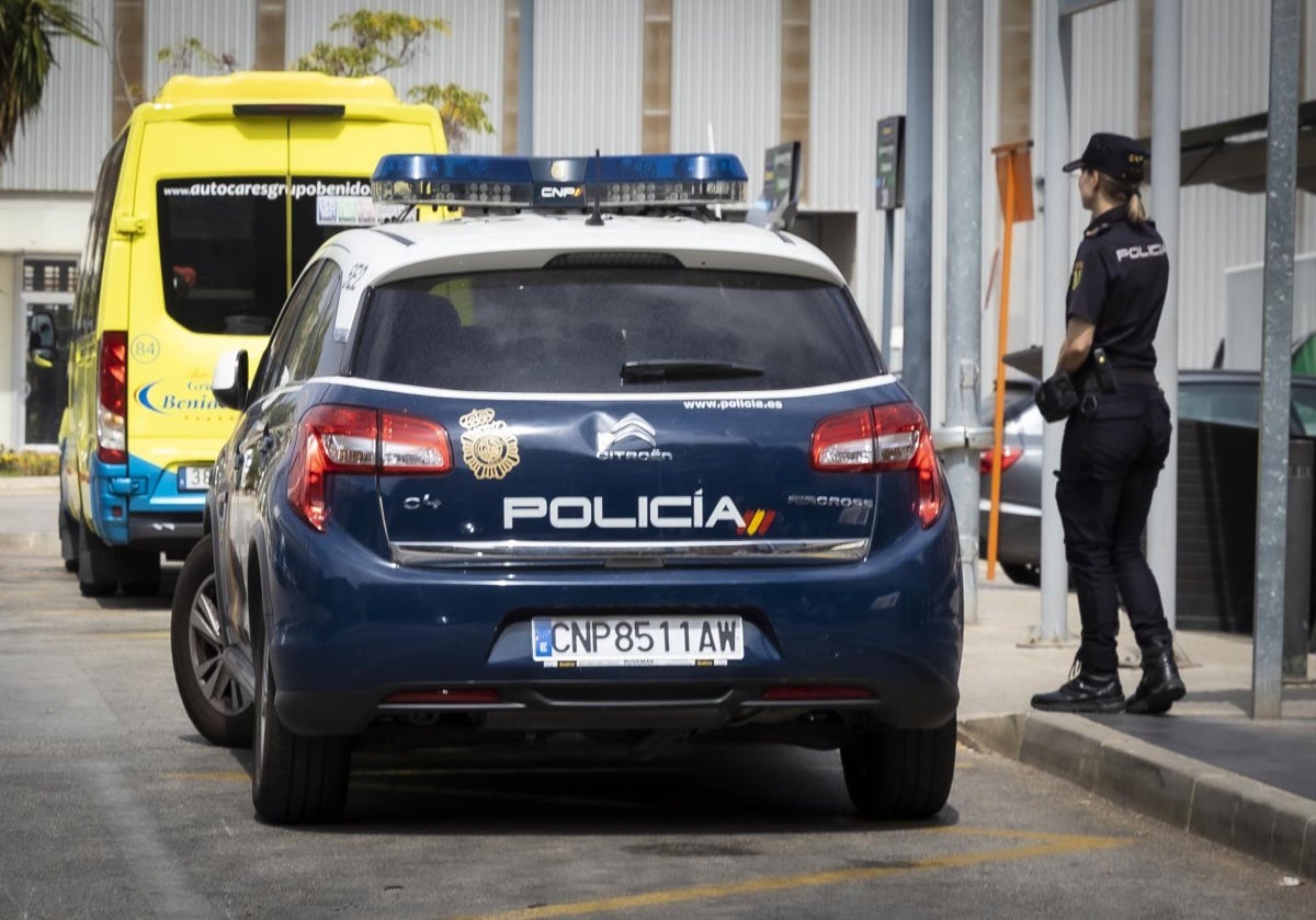 Una agente de la Policía Nacional junto a un vehículo patrulla