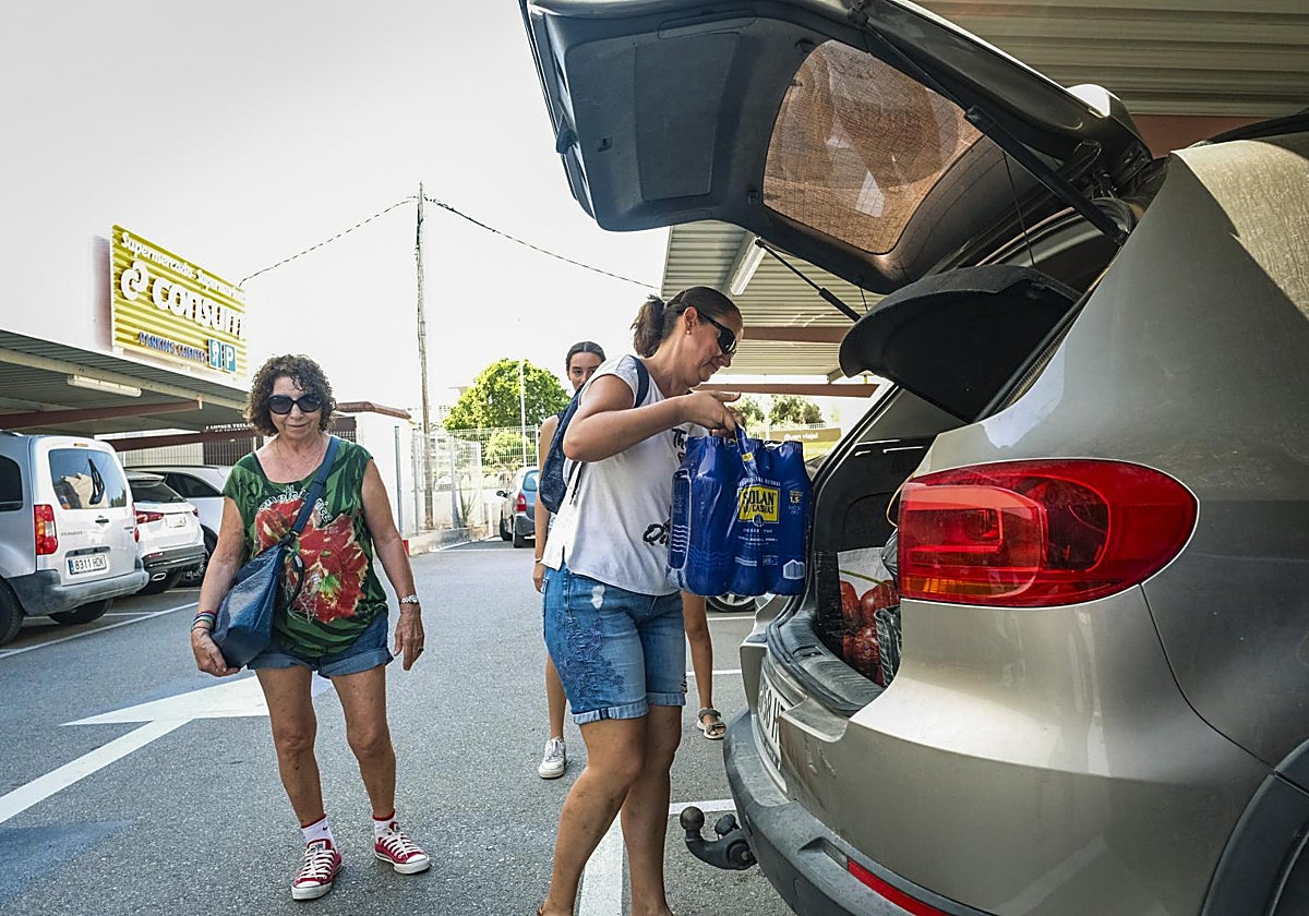 Una mujer carga agua embotellada en su coche junto a un supermercado en Teulada-Moraira