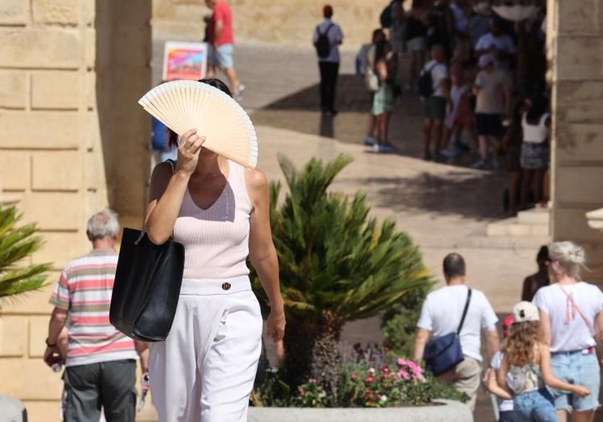 Una mujer se protege del calor mientras pasea por el Puente Romano