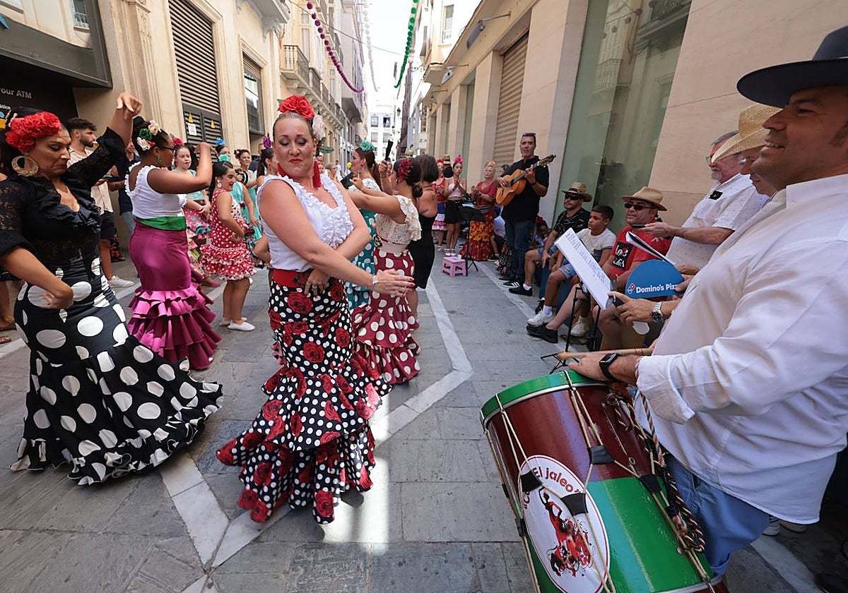 Mujeres con trajes de flamenca bailan en una calle del centro de Málaga
