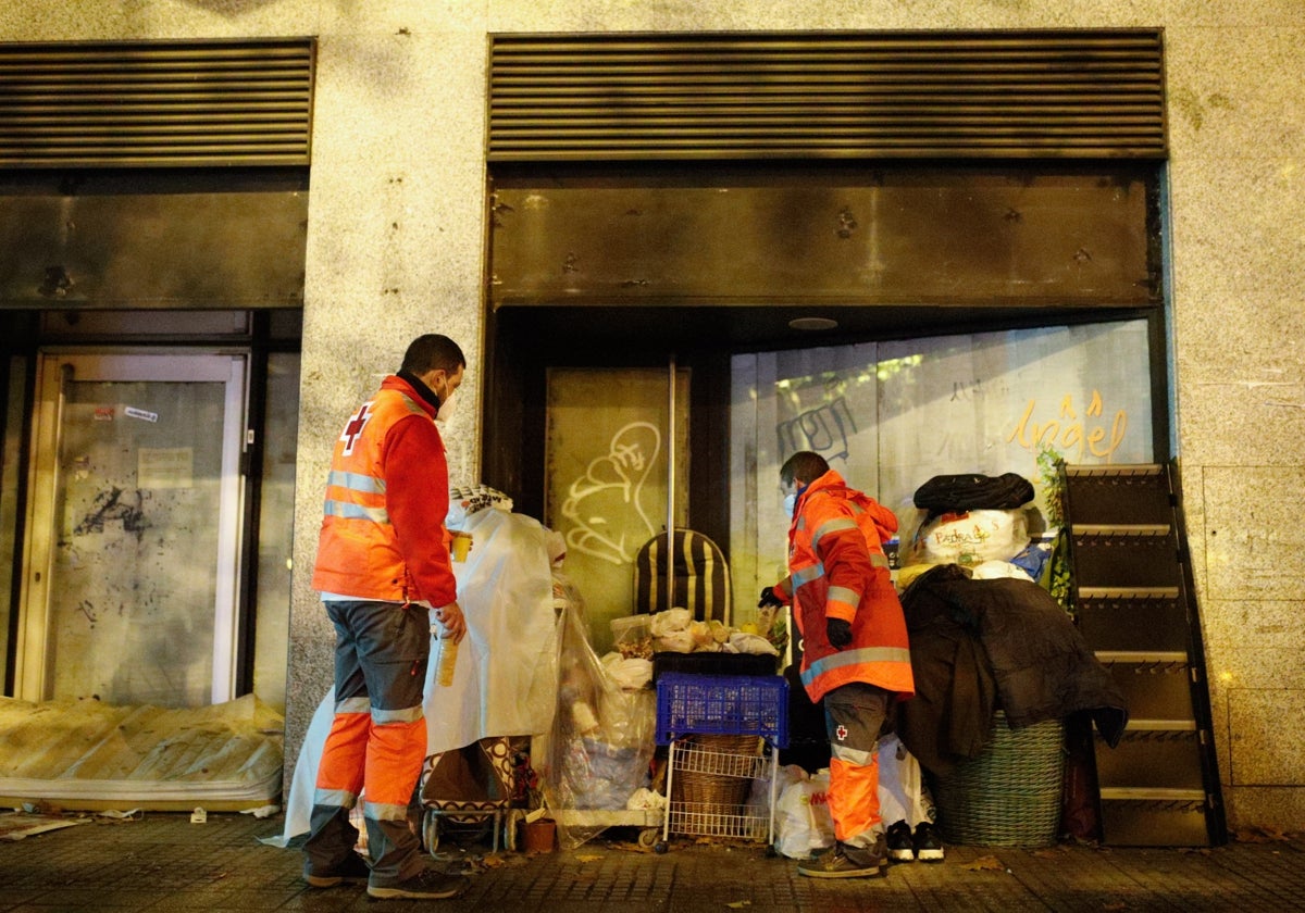 Dos personas e la Cruz Roja atienden a otra que vive en la calle