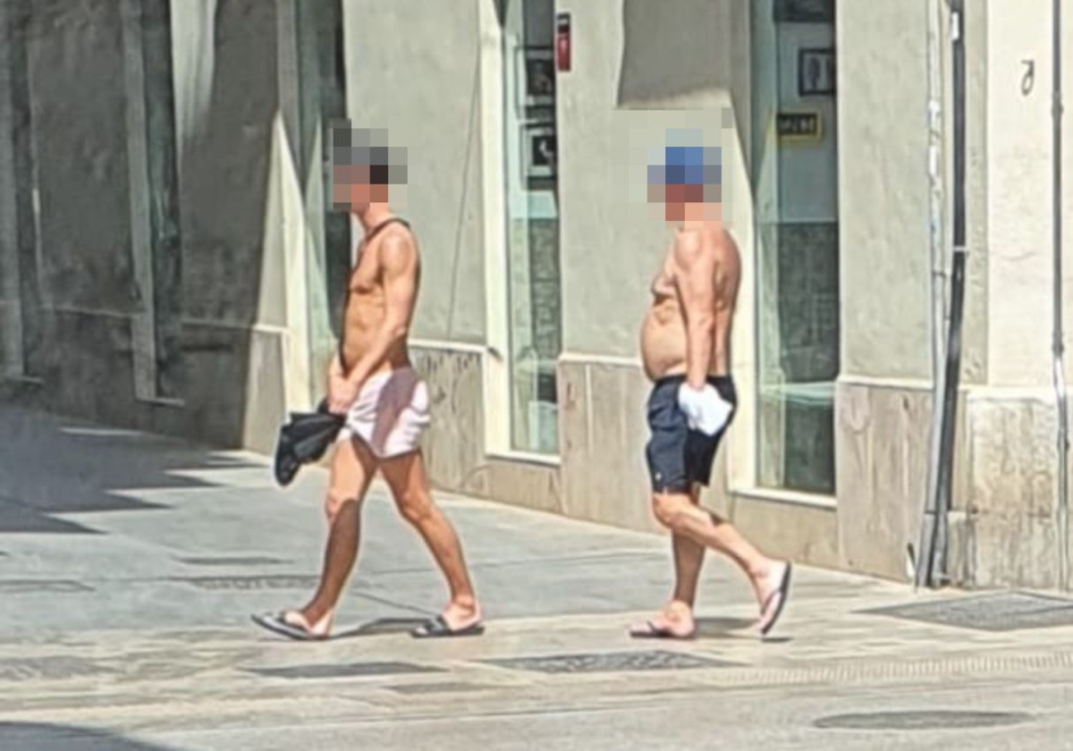 Dos turistas pasean en bañador por el centro de Málaga